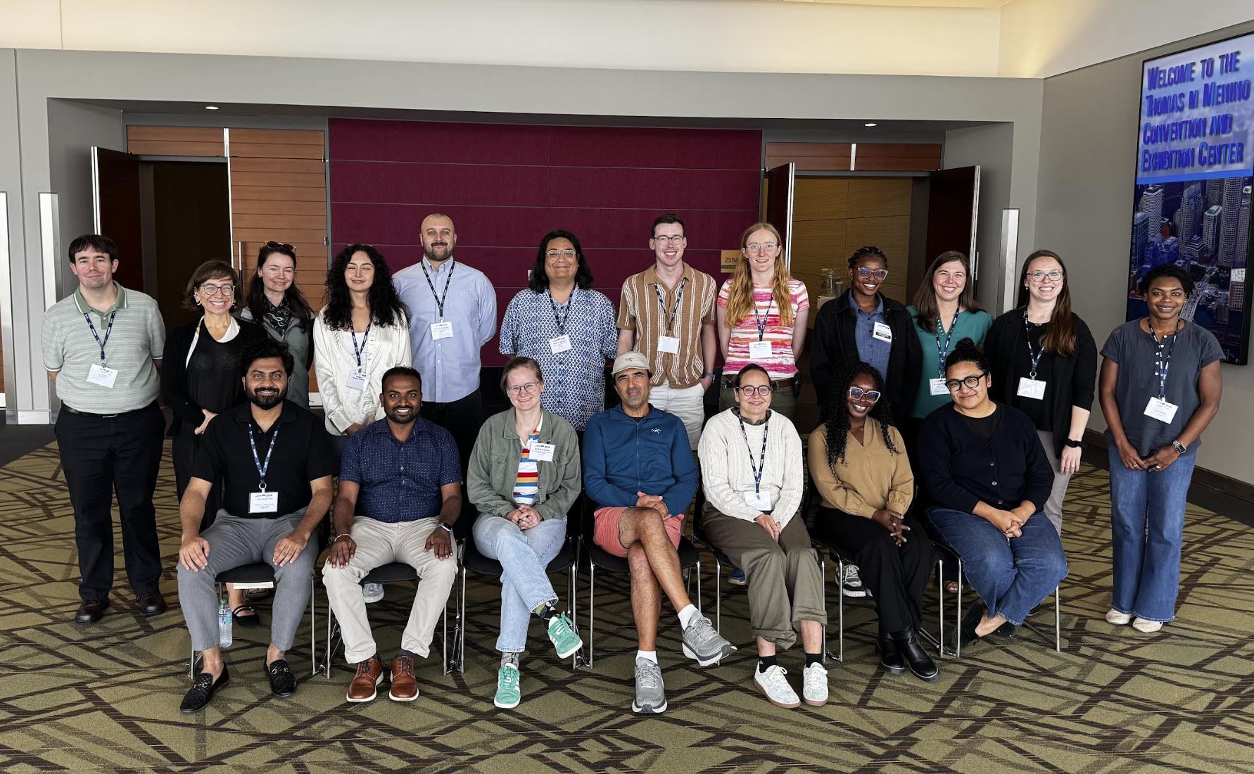 A photo of the participants and presenters for the 2026 Preparing to Teach Statistics and Data Science workshop. There are two rows of people, the first row is sitting and the second row is standing. There are a total of 19 people in the photo.